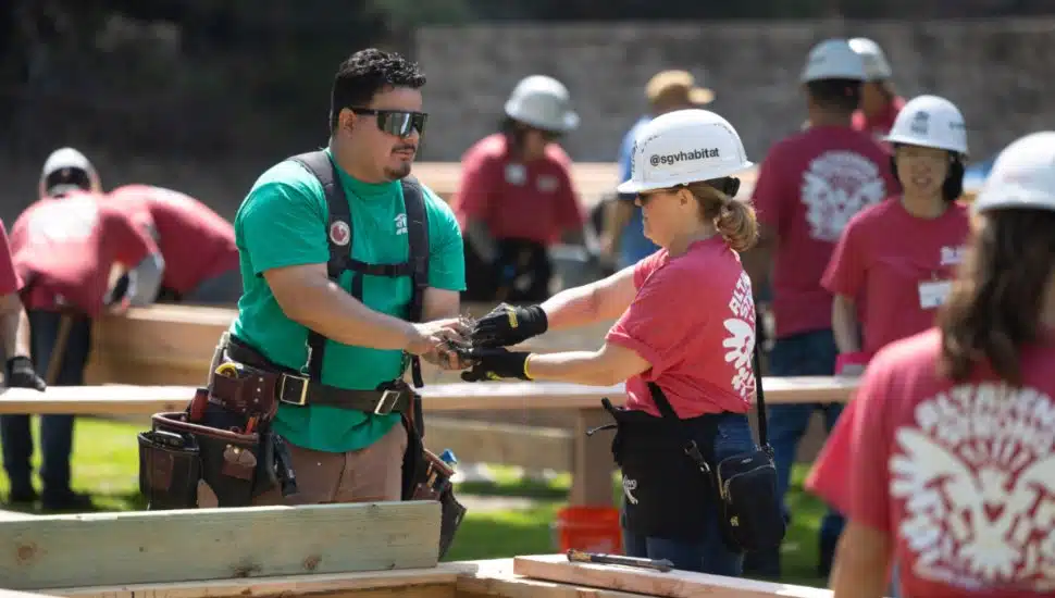Volunteers wearing safety gear collaborate on a home construction project during Habitat for Humanity’s Walls of Hope initiative in Altadena.
