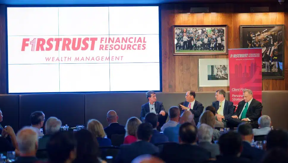 Panelists discuss market in front of audience.