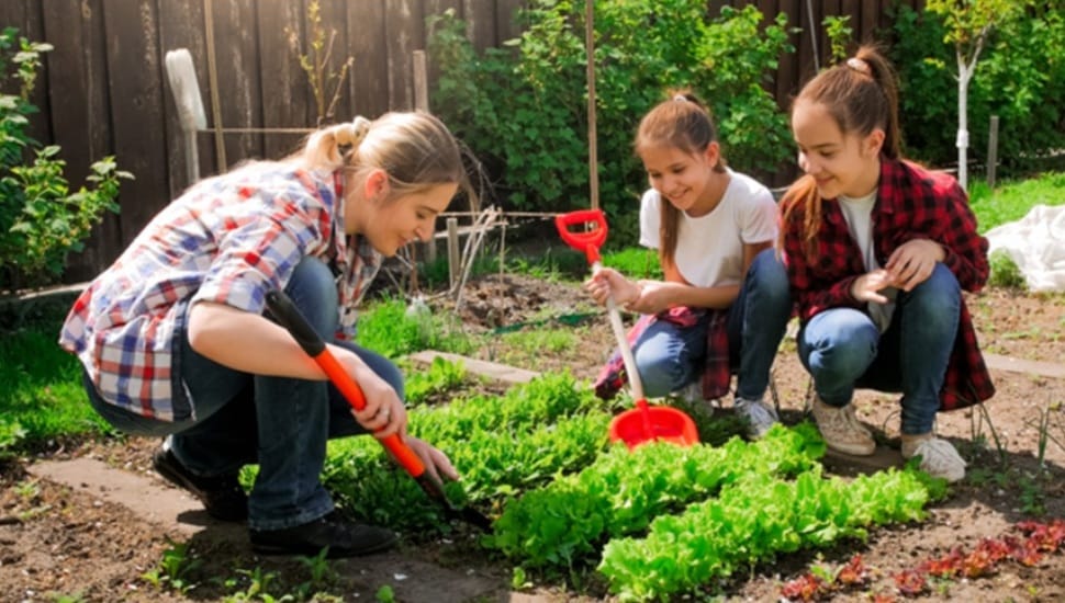 Young woman works in the garden with her two daughters.