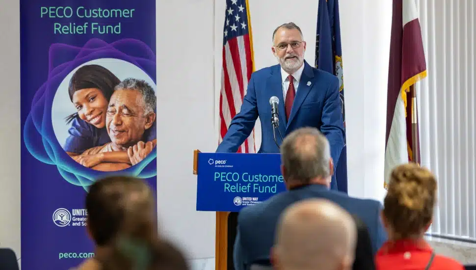 Middle-aged male in blue suit addresses the media at a press conference.