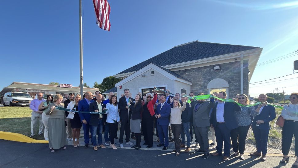 Ribbon-cutting ceremony outside Propell Credit Union's new West Goshen branch, with community members, staff, and local officials gathered under a large American flag.