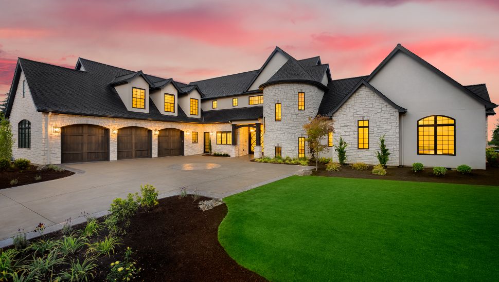 Expensive home with white exterior with sunset in background.