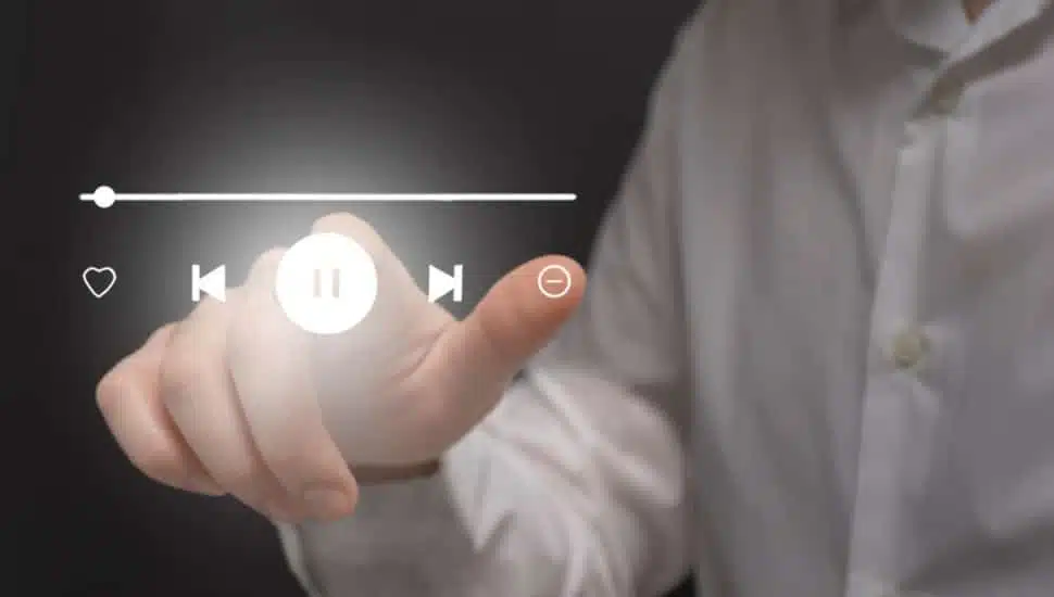 Businessman hand touching virtual icon of media player on virtual screen.