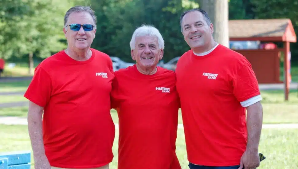 Three male bank employees in red t-shirts.