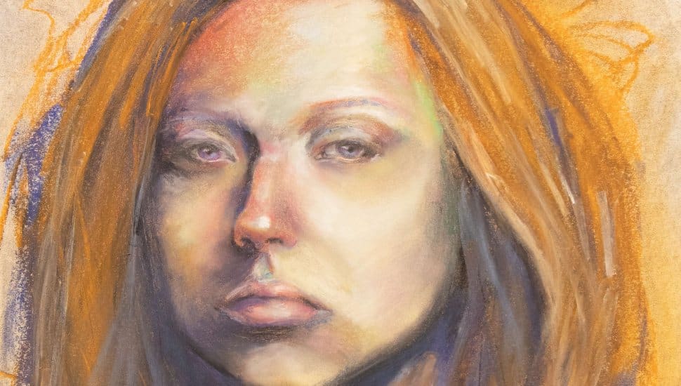 Pastel portrait of a young woman with long reddish-brown hair, expressive eyes, and a serious expression, created by a student artist for the DCCC AFA Foundations Exhibition.