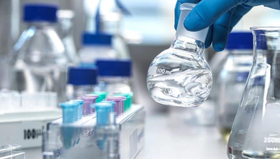 Gloved hand putting down a little glass bottle in a lab.