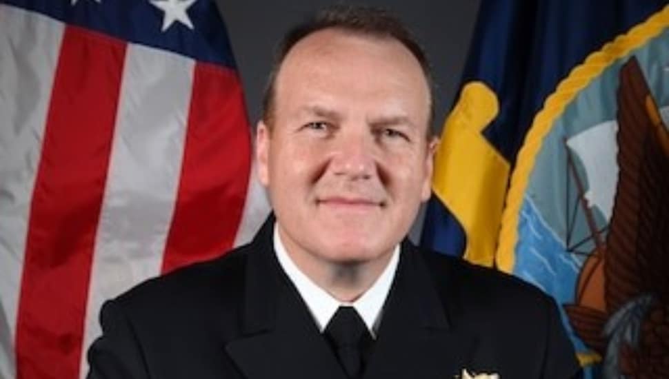 Adm. Tom Anderson headshot with American flag behind.