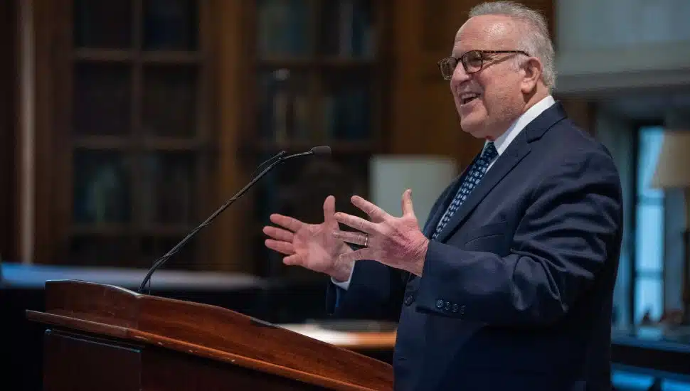 Former Pennsylvania State Senator Andrew Dinniman speaking at a podium during a West Chester University event, addressing the audience with an engaging gesture.