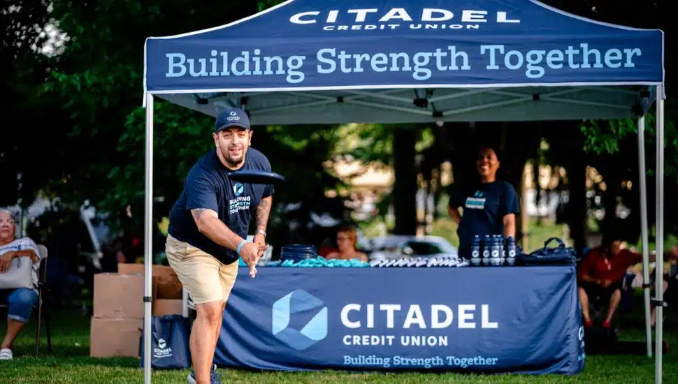 Credit union employee throws a frisbee.