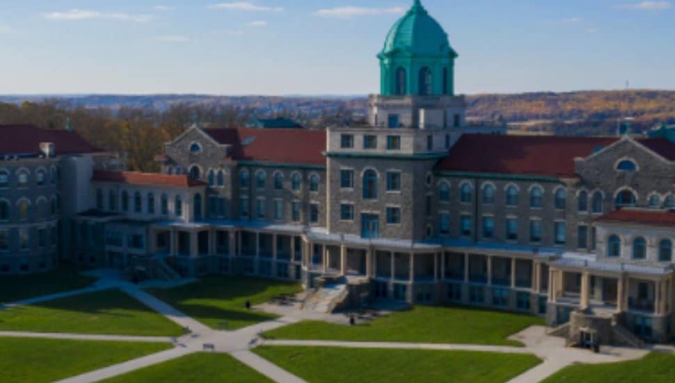 Immaculata University main campus in East Whiteland Township, Pennsylvania, featuring the iconic domed main building surrounded by green lawns and walkways on a sunny day.