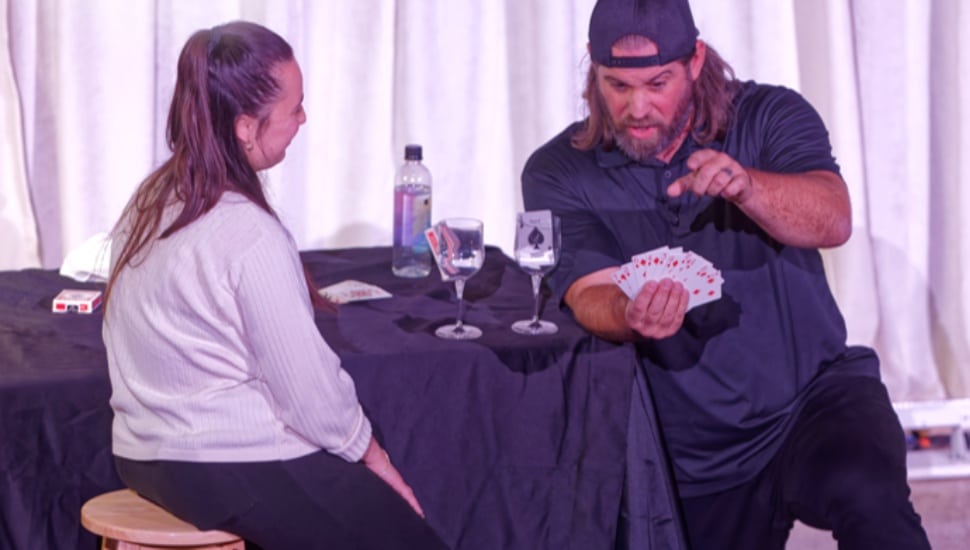 Man performs magic trick for corporate audience.