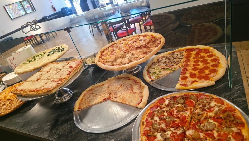 Pizza pies in glass case.
