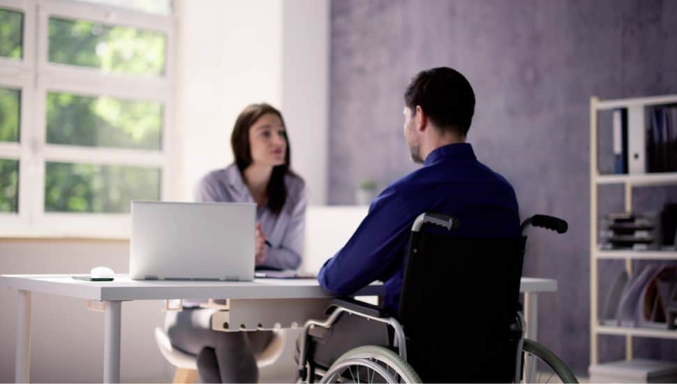 Man in a wheelchair sits for a job interview.