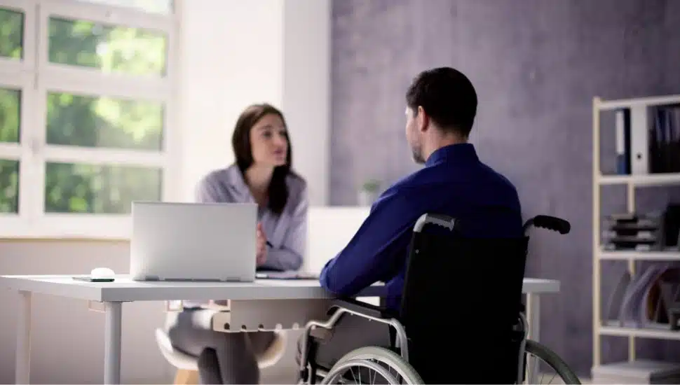 Man in a wheelchair sits for a job interview.