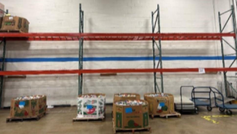 Empty warehouse shelves at the Chester County Food Bank with only a few bins of donated food remaining, illustrating the impact of delayed state funding and reduced food donations.