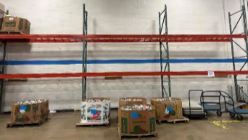 Empty warehouse shelves at the Chester County Food Bank with only a few bins of donated food remaining, illustrating the impact of delayed state funding and reduced food donations.