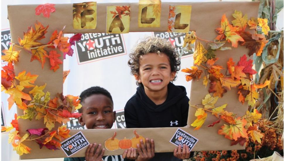 Two kids hold a leaf picture frame at Fall Fest.