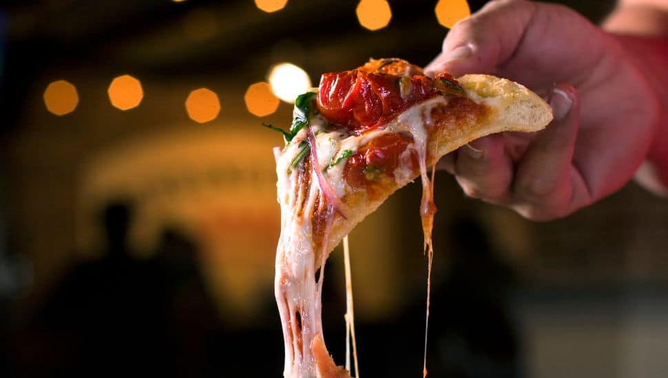 Person pulls pizza slice.