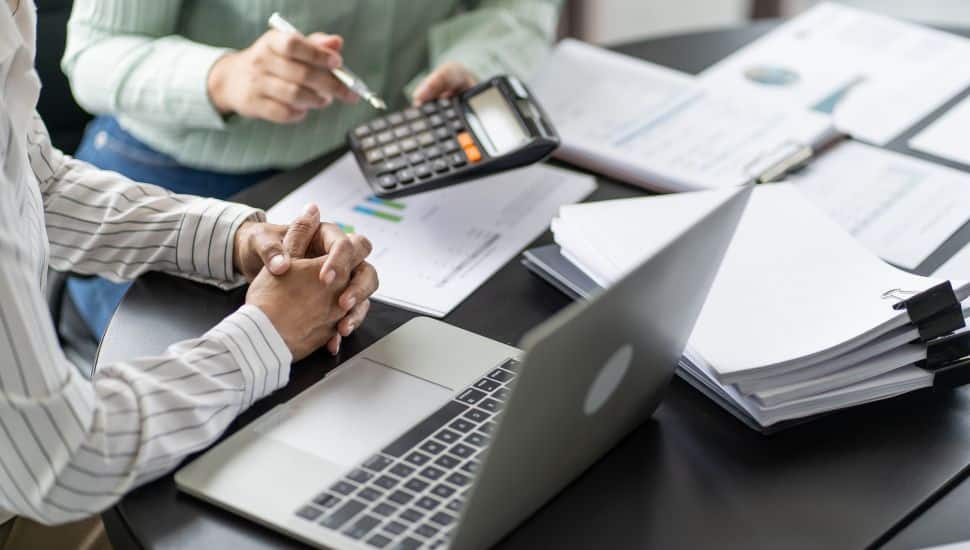 Two people doing taxes surrounded by papers.