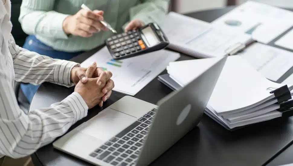 Two people doing taxes surrounded by papers.