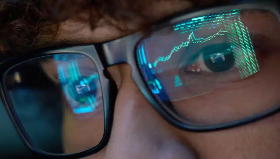Reflection of index funds in glasses of businessman.