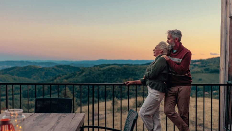 Older couple stares at horizon from balcony.