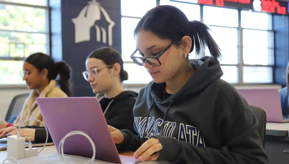 Students working on laptops in a classroom at Immaculata University, focused on coursework.