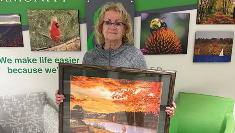 Woman holds her framed photograph for calendar contest.
