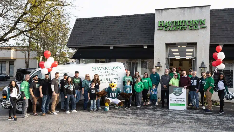 Eagles cheerleaders and bank representatives pose for picture with employees of carpet company.