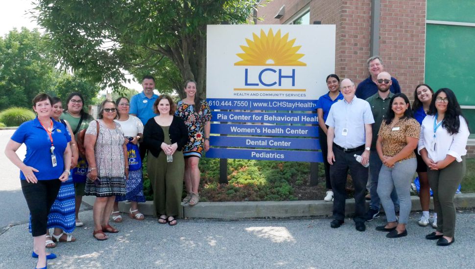 Group of people standing next to LCH Health & Community Services signage.