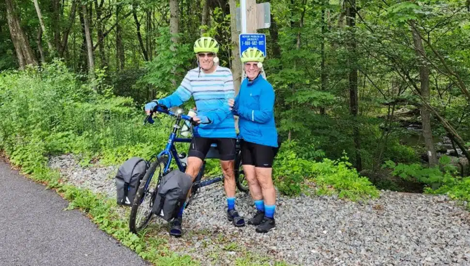 Older couple pose for picture on bike path.