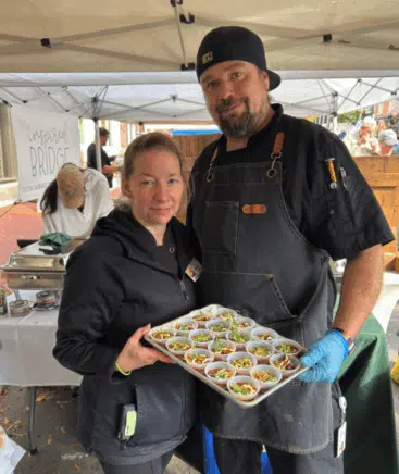 Brianna Morales and Chef Evan Neal holding a tray of chili cups.