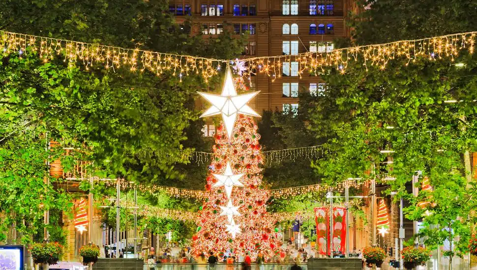 A lit holiday tree surrounded by a holiday festival.