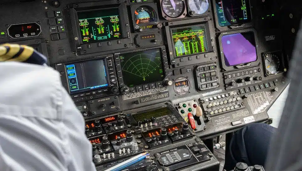 Two pilots in a cockpit looking at control panel