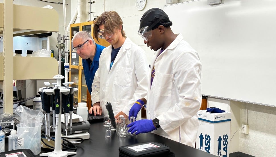 Professor Domhnall OShaughessy (far left) and students David Young (left) and Jeremiah Valcourt (right) test samples in the lab.