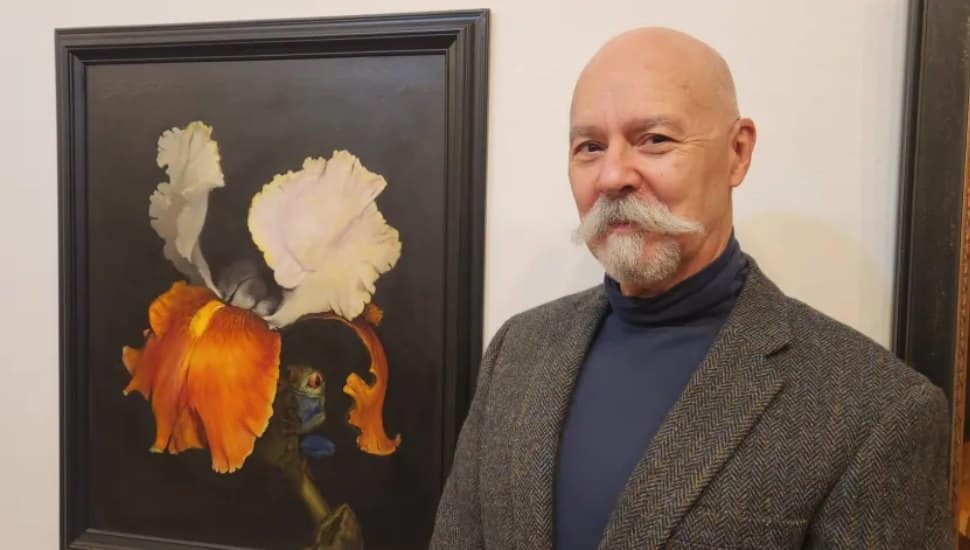 Adrian Martinez standing next to one of his paintings.