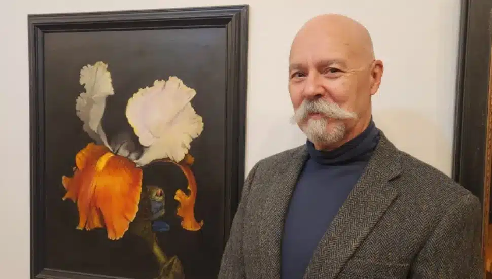 Adrian Martinez standing next to one of his paintings.