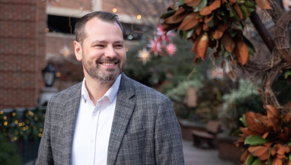 Man in gray sport coat and white dress shirt smiles.