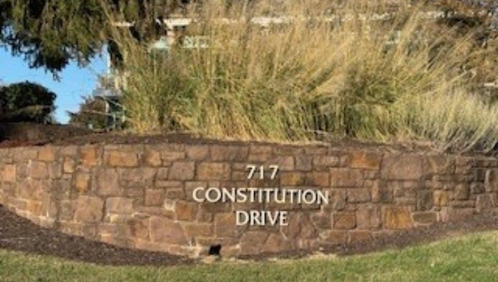 Stone monument sign displaying “717 Constitution Drive” at the entrance to the office building in Exton, Pennsylvania.