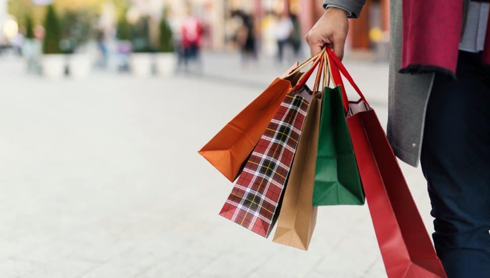 Man holding shopping bags with presents on the street.