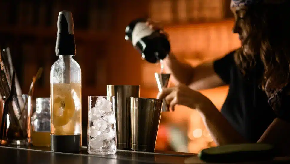 A bartender prepares a cocktail at a dimly lit bar.