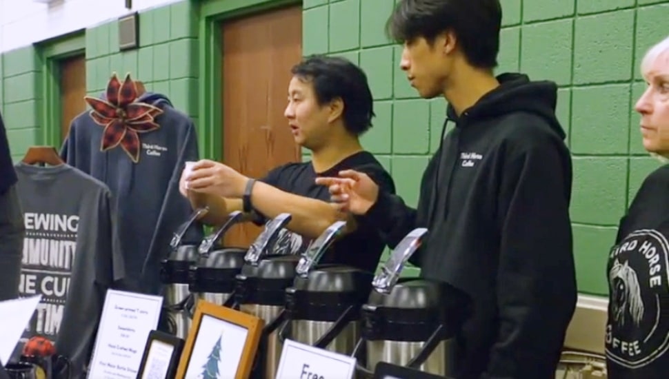 Josiah Kessler, the adopted son of Mark and Beth Kessler, serves customer some Third Horse coffee at a community event. Right now, the coffee and merchandise is sold online out of Brookhaven but the hope is to eventually open a brick-and-mortar store.