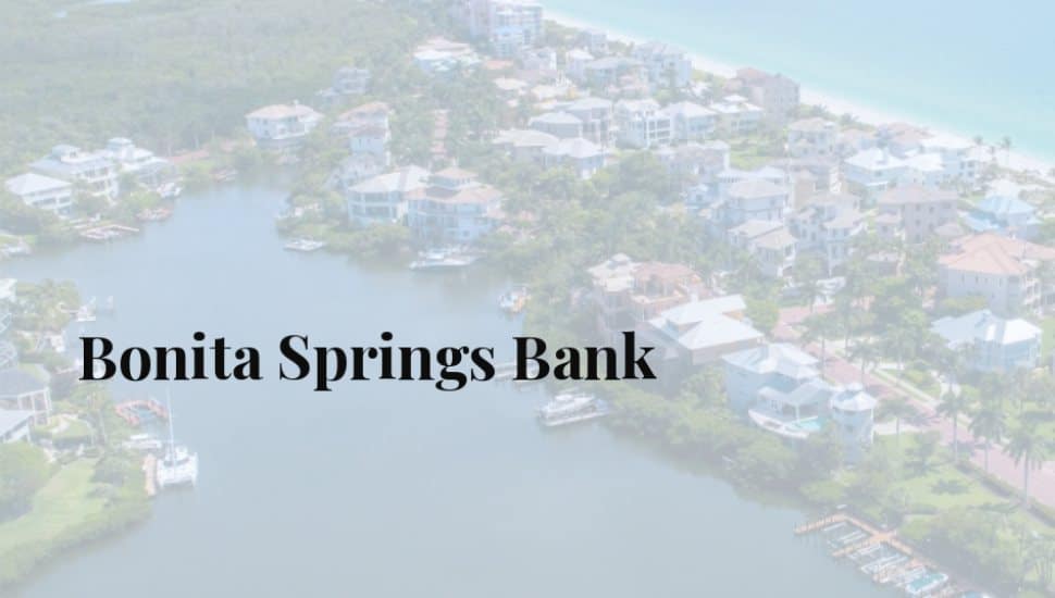 Aerial view of Bonita Springs waterfront neighborhood with canals, coastal homes, palm trees, and the Gulf of Mexico in the background.