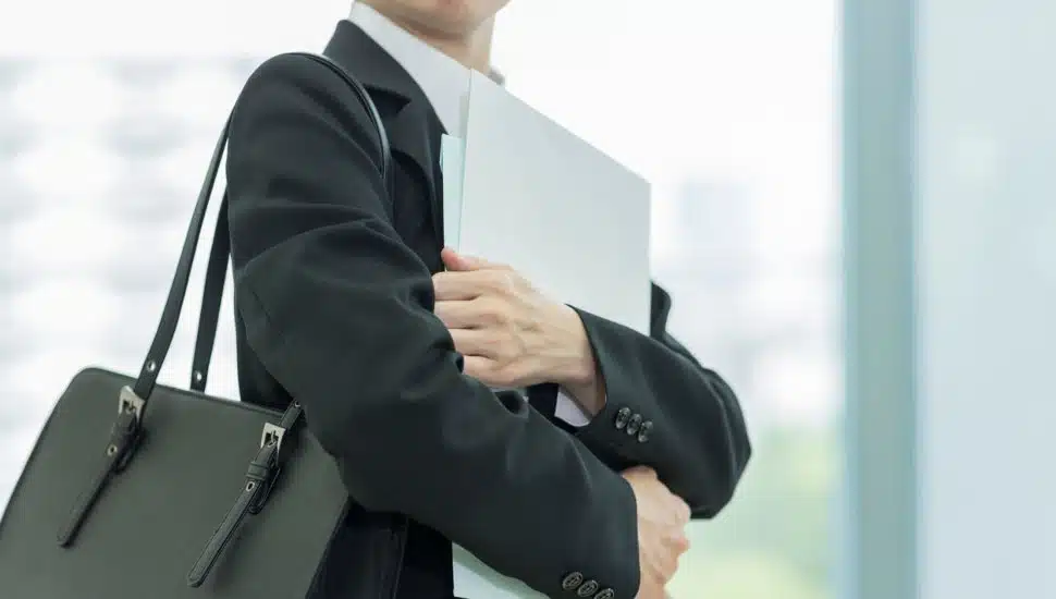 Person in a business suit holding a portfolio and briefcase, symbolizing professionalism and career readiness.