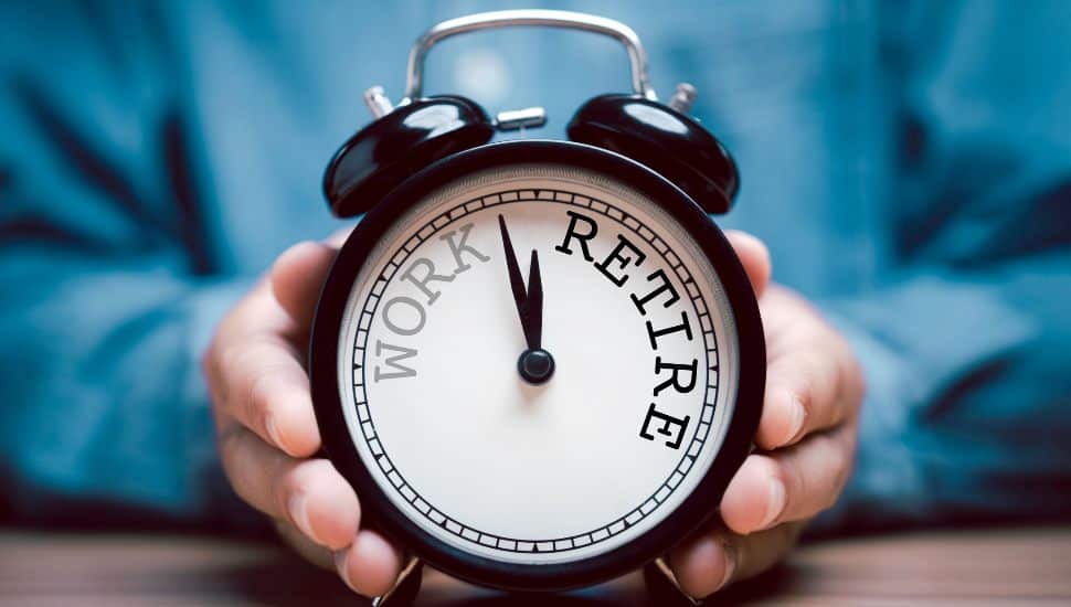 Person holding analog clock with words Work and Retirement.