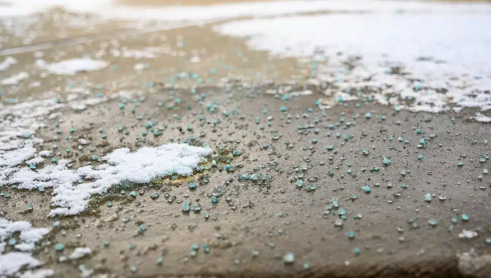 Road salt on sidewalk with some snow.