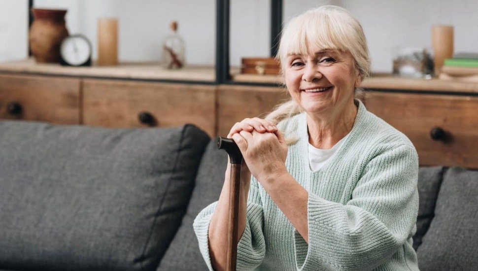 A senior woman smiles as she sits comfortably.
