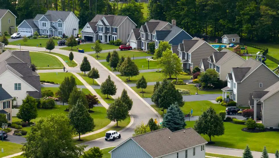 Suburban neighborhood aerial view with lots of homes and a road.
