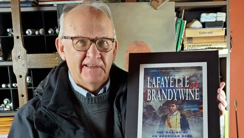 Bruce Mowday holding a painting/book cover.