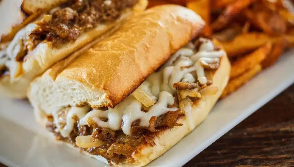 A cheesesteak and fries on a plate.